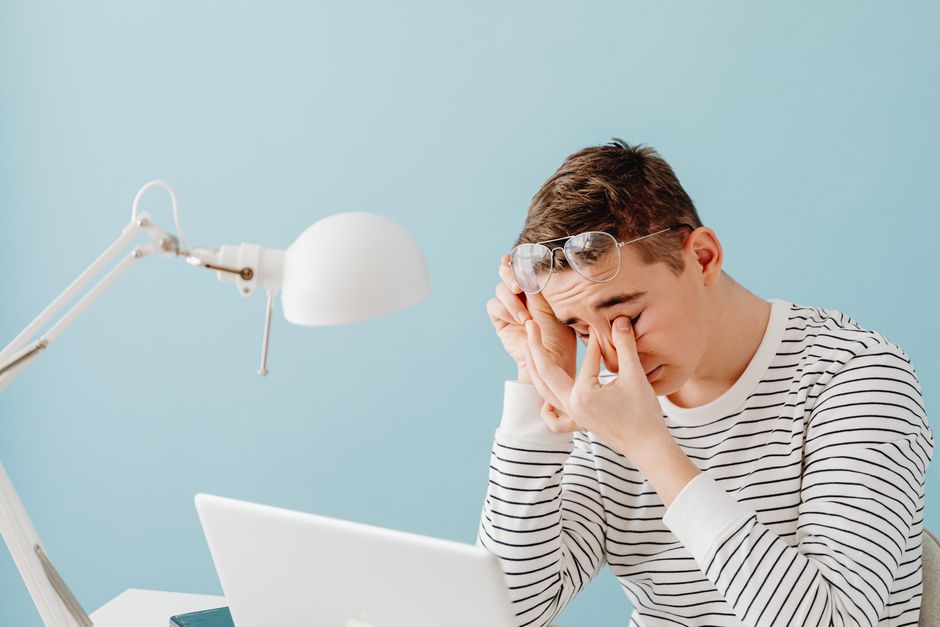 tired person rubbing dry eyes at computer