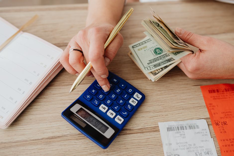 person calculating budget with calculator notebook