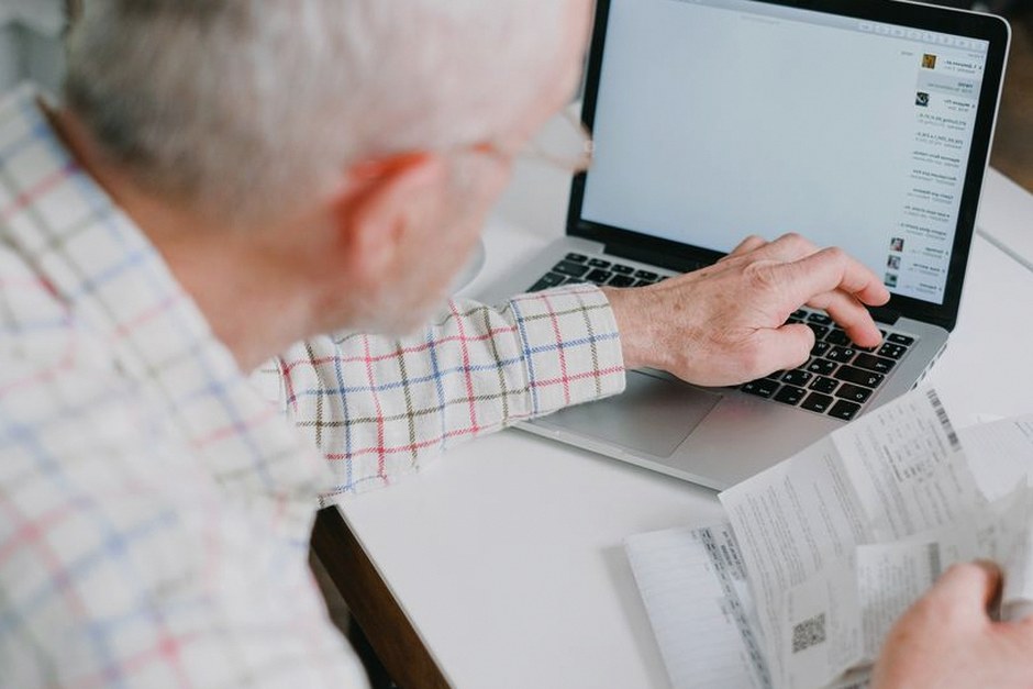 elderly man checking bank statement calculator