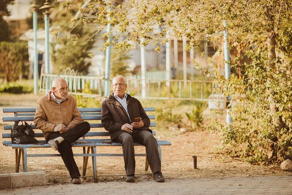 senior friends talking outdoors bench sunny day