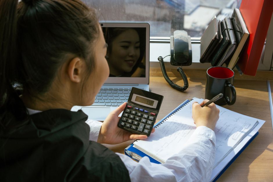 korean woman comparing prices on calculator and laptop