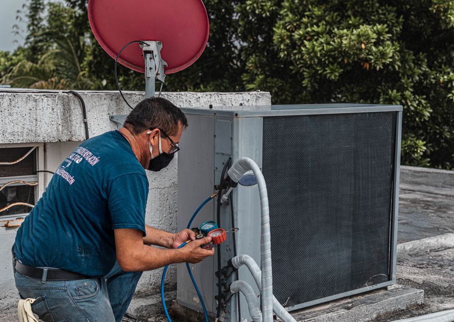 person cleaning air conditioner filter with brush