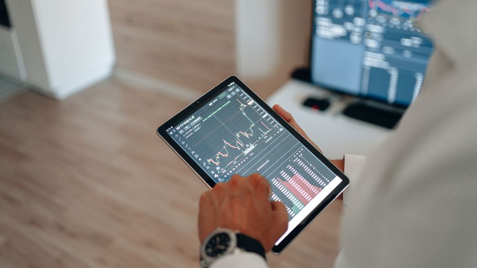 elderly person using tablet stock market chart