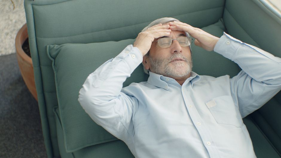 elderly person with headache resting on sofa