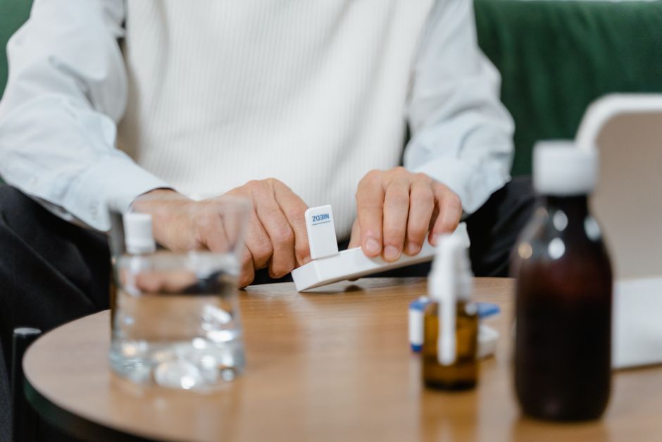 senior person sorting medicine at home kitchen table