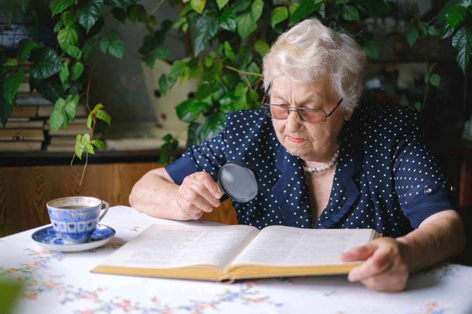 elderly person reading contract with magnifying glass