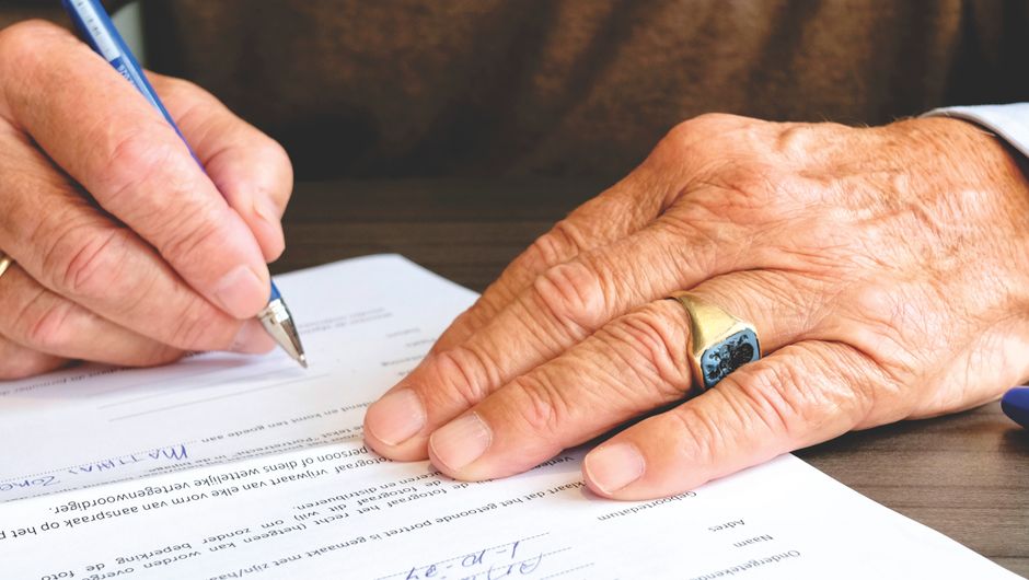 senior person signing contract with pen