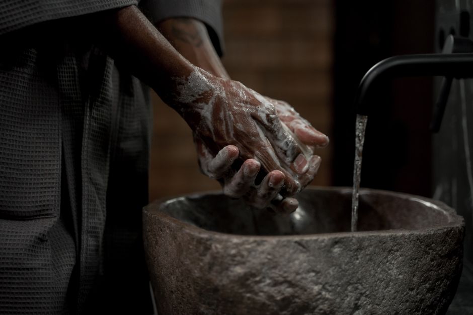 person washing feet warm water basin