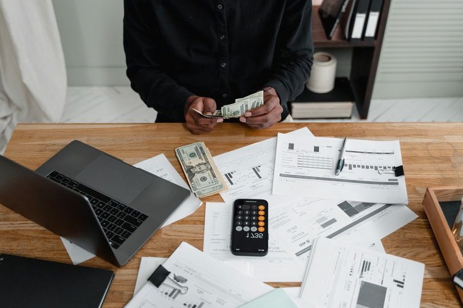 person managing money laptop desk
