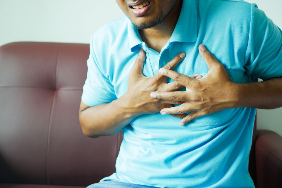 person holding chest pain warning sign