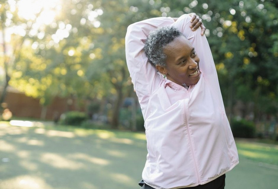 elderly woman stretching outdoors sunlight