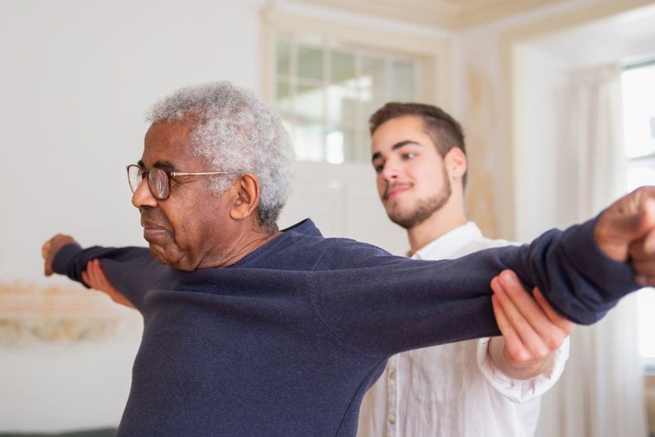 caregiver helping elderly with chair squat exercise