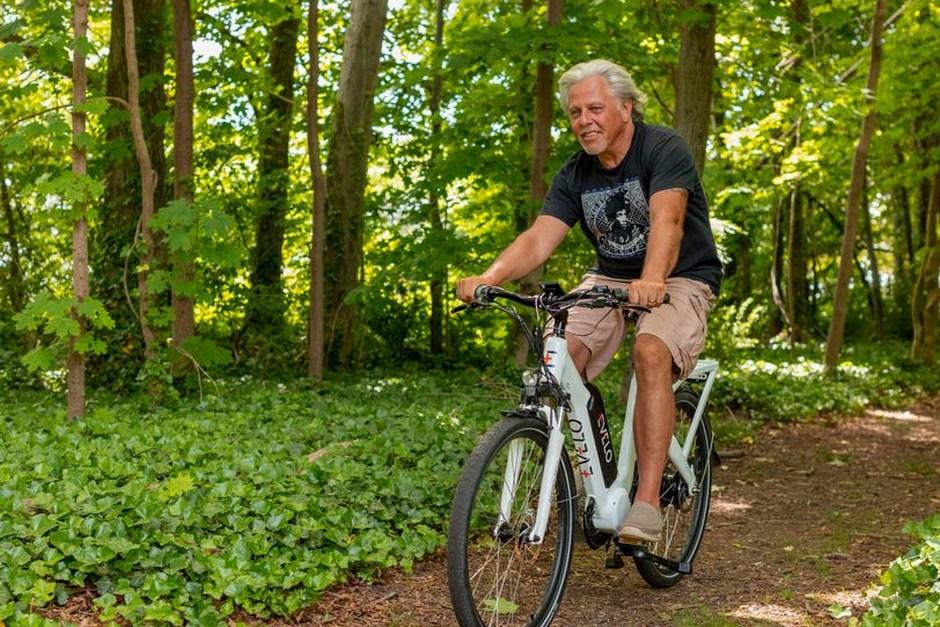 senior man riding electric bicycle park path