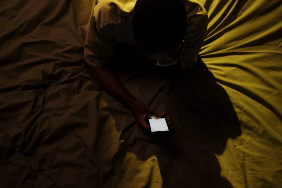 person using smartphone in bed dark room