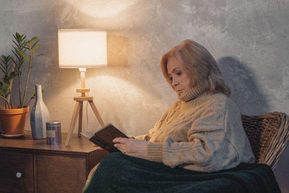 elderly woman reading under warm lamp light